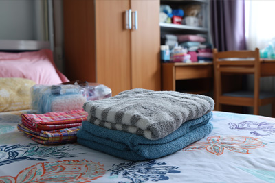 Colorful folded towels and wash cloths on a bed in a dorm room